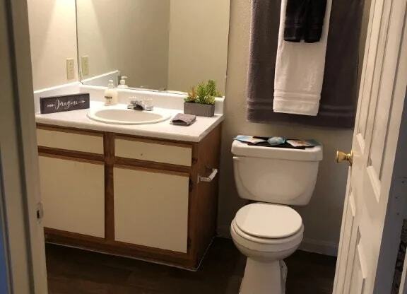 a bathroom with a toilet sink and mirror at GABLE HILLS Apartments, TULSA, Oklahoma