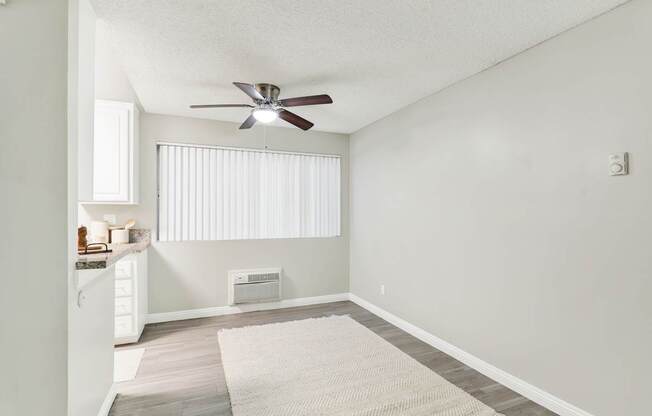 A room with a ceiling fan and a window with blinds.