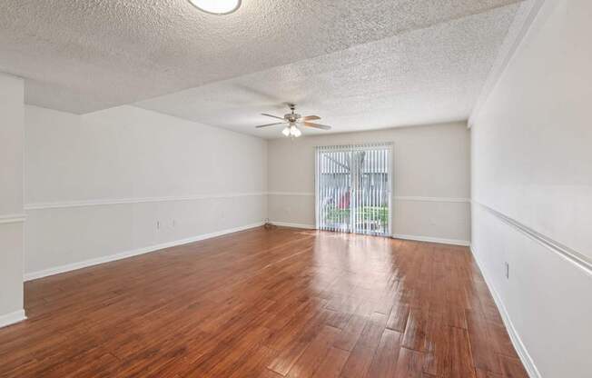 A room with wooden flooring and a ceiling fan.