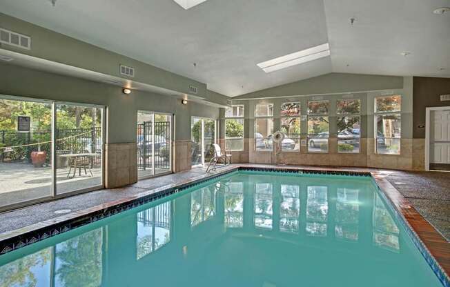 A large indoor swimming pool with a glass wall and sliding doors.