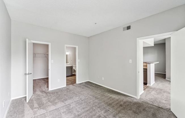 the living room of an apartment with carpet and a door to the bathroom