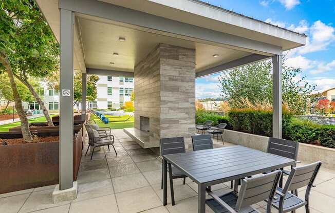 A patio with a table and chairs under a roof.