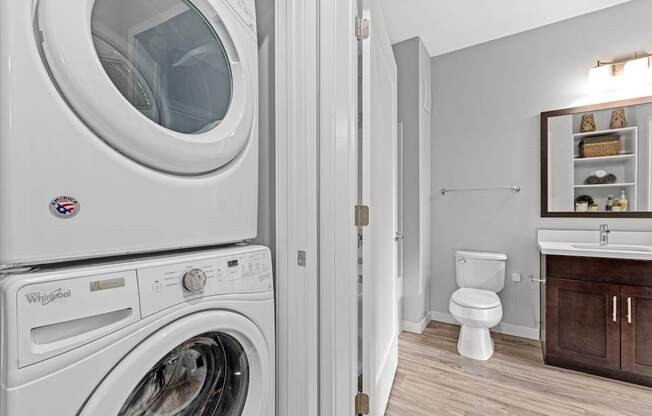 A Whirlpool washing machine is in a laundry room with a toilet and sink.