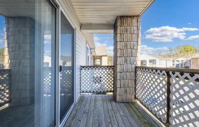 A wooden deck with a lattice fence and a glass door leading to a balcony.