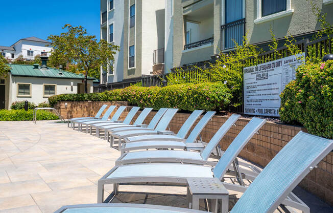 A row of sun loungers are arranged on a patio.