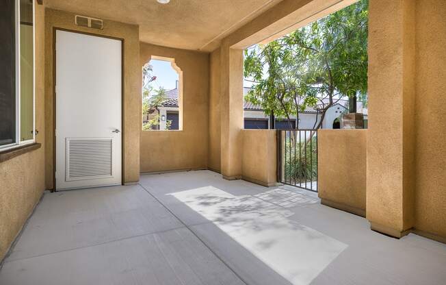 a patio with a white door and a tree in the background