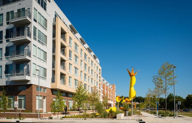 a large yellow sculpture in front of an apartment building