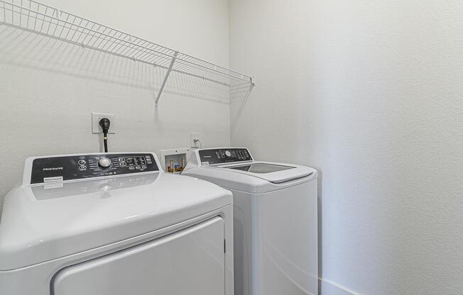 a white laundry room with two washes and a dryer at The Fitzroy San Marcos, San Marcos, TX