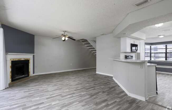 an empty living room with a fireplace and a ceiling fan