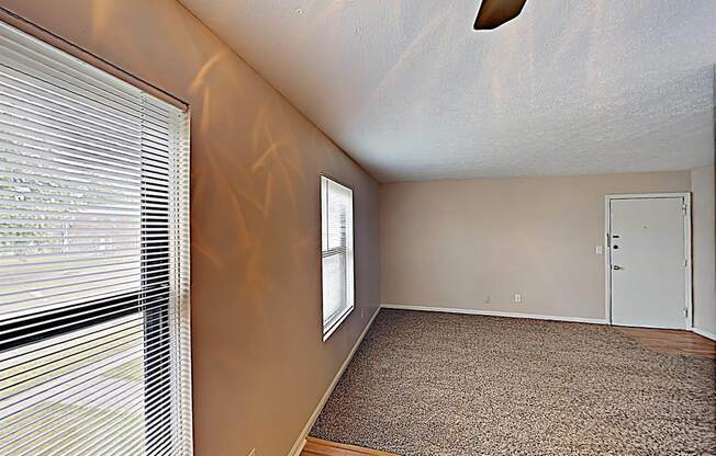 an empty living room with a large window and a door