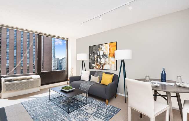 a living and dining area with a couch table and chairs and a large window with a city at Columbus Plaza, Chicago, 60601