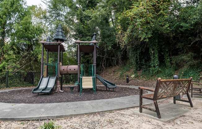 A playground with a green slide and a wooden bench.