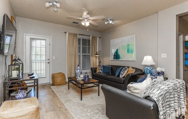 a living room with couches and a coffee table and a ceiling fan