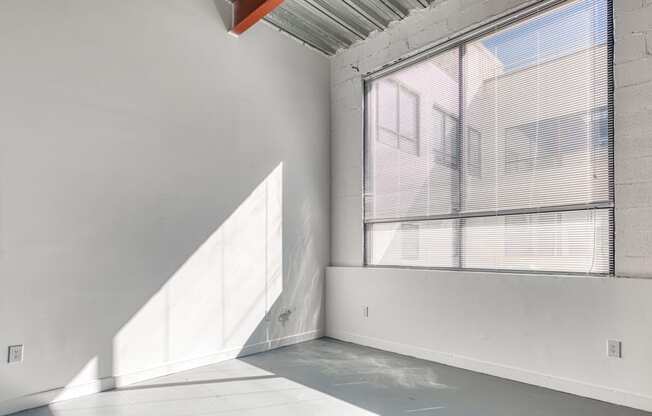 an empty room with a large window and a white wall