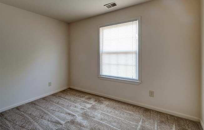 Guest Bedroom with neutral colored walls and a large window at Briarwood Apartments in Columbus, IN