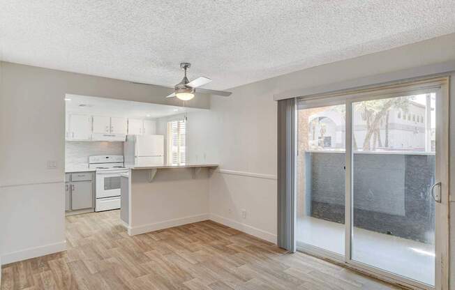 A room with a kitchen area and a sliding glass door.