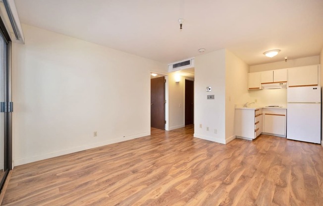 a living room and kitchen with a wood floor and white appliances