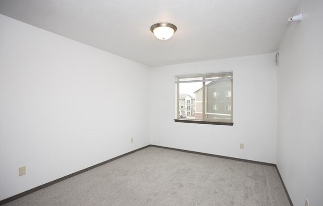 an empty room with a window and carpet