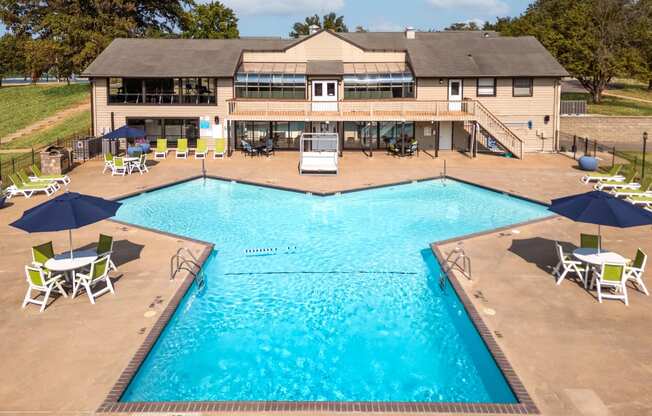 a swimming pool with chairs and umbrellas in front of a resort style pool