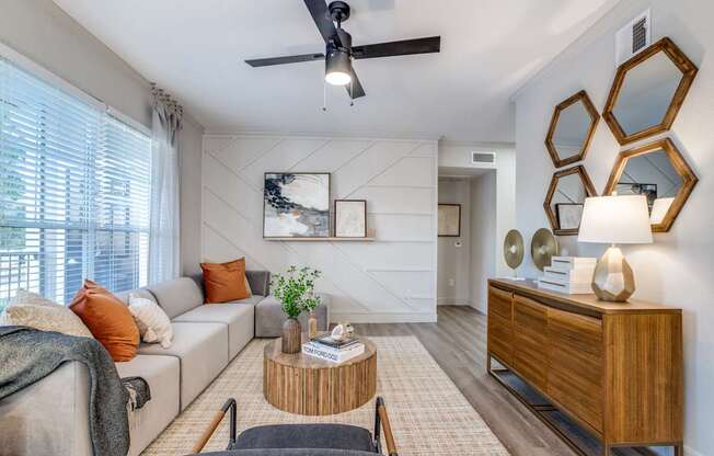 A living room with a grey couch, a wooden coffee table, and a ceiling fan.