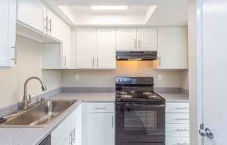 a kitchen with white cabinets and black appliances