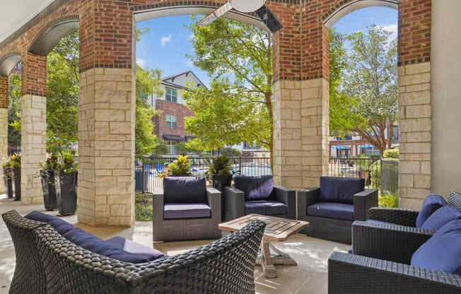 a patio with chairs and a table and brick columns