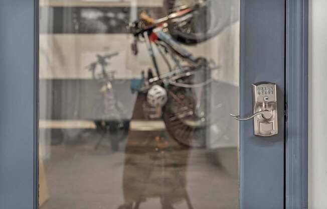A person is standing in front of a glass door with a bicycle reflected in it.