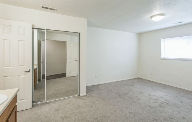 an empty living room with a mirror and a bathroom