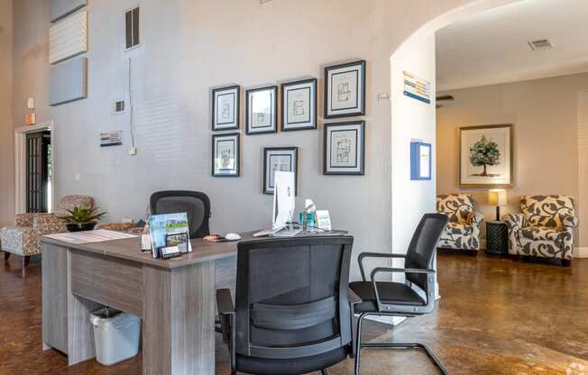 an office with a desk and chairs in front of a wall with photos on it