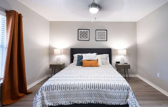 A bedroom with a large bed and two lamps.