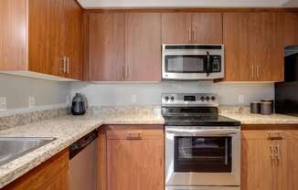 A kitchen with wooden cabinets and a stainless steel oven.