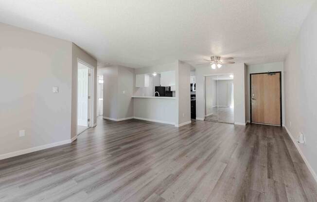 A spacious room with wooden flooring and a ceiling fan.