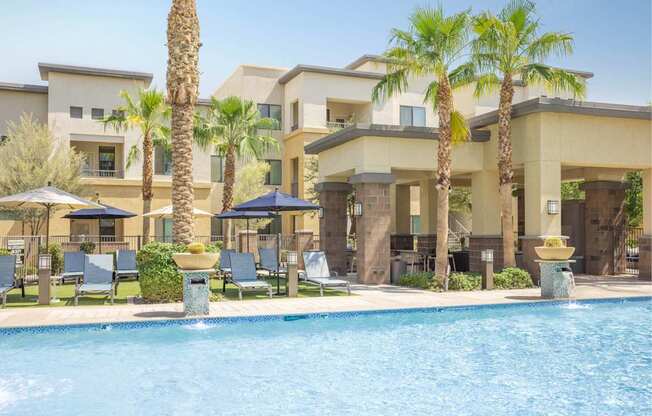 A pool surrounded by palm trees and lounge chairs.