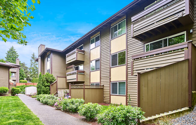 Exterior view of personal patios or balconies, manicured grounds and building, and blue skies in the background at Heritage Grove, Renton, WA.