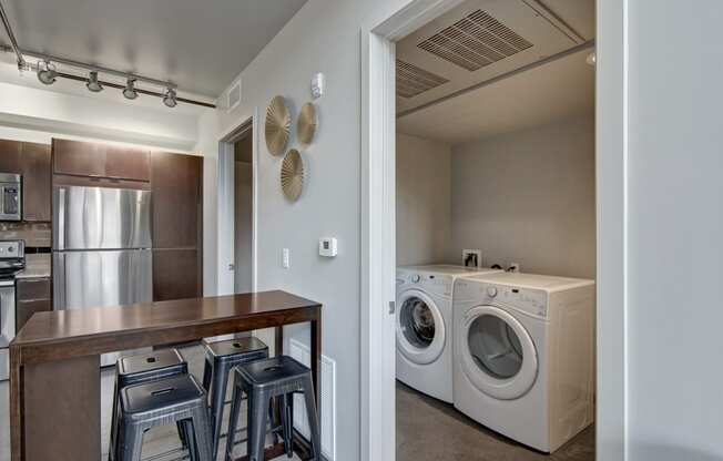a kitchen with a washer and dryer and a table with stools