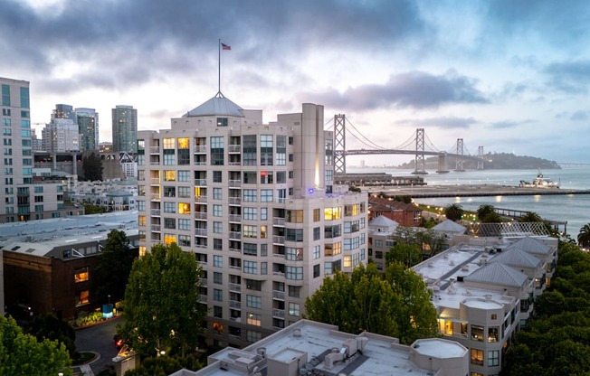 A cityscape with a bridge in the background and a building with a flag on top.