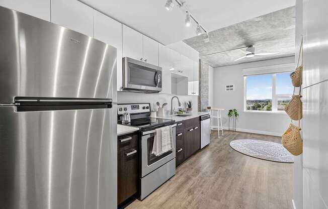 A modern kitchen with a stainless steel refrigerator and wooden flooring.