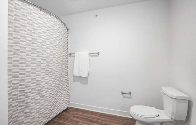 A bathroom with a toilet and a shower curtain at Meadowbrooke Apartment Homes in Kentwood, MI 49512