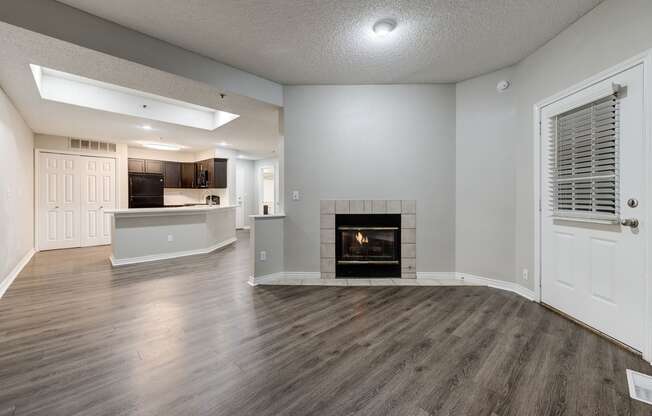 an empty living room with a fireplace and a kitchen at Ashford Belmar Apartments, Lakewood, Colorado