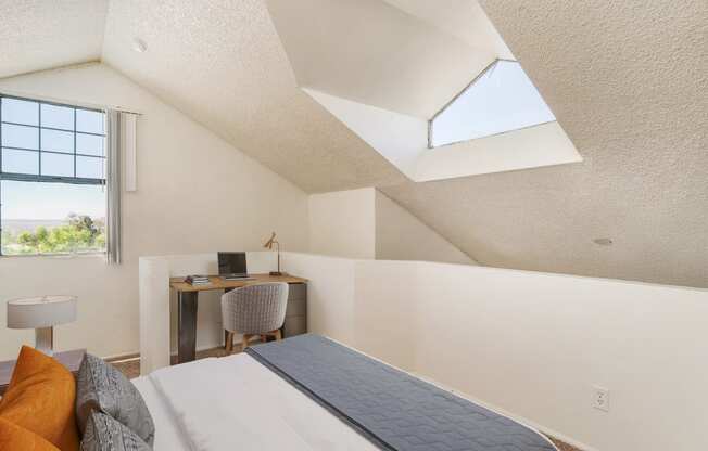 a bedroom with a bed and a desk with a window