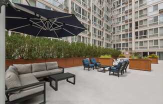 an outdoor lounge area with couches chairs and umbrellas