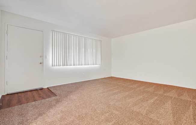 Living room with carpeted floors, wood style floors on the door entry area