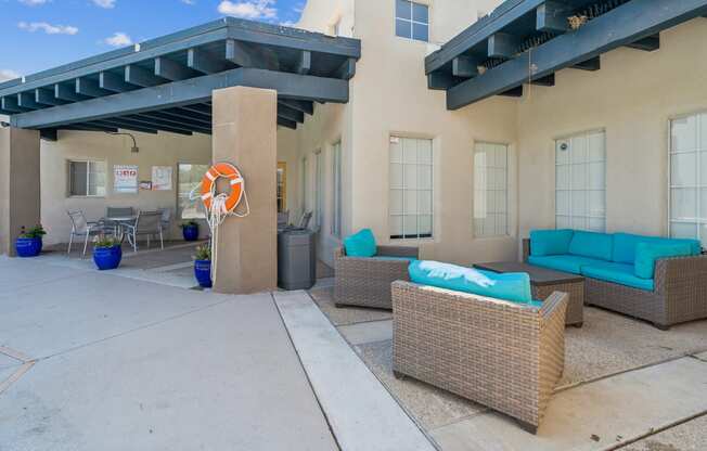 a patio with couches and chairs in front of a house