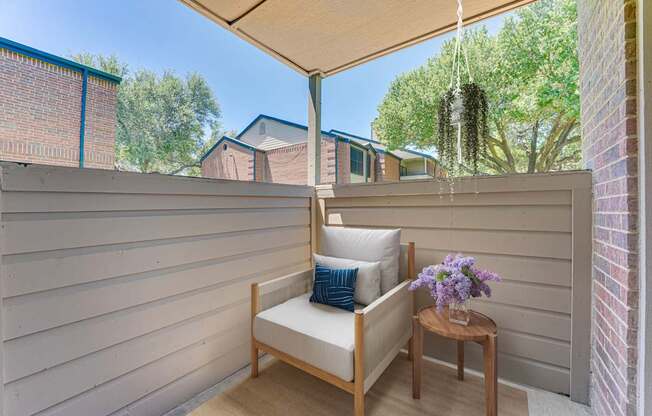A wooden chair with a cushion and a small table with flowers on it.
