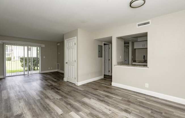 an empty living room with wood flooring and a sliding glass door