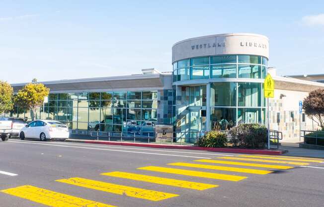 a modern glass building with a yellow crosswalk in front of it