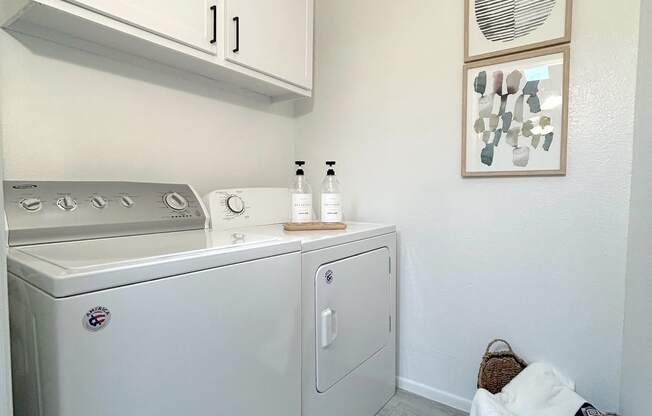 a small laundry room with a washer and dryer and white cabinets