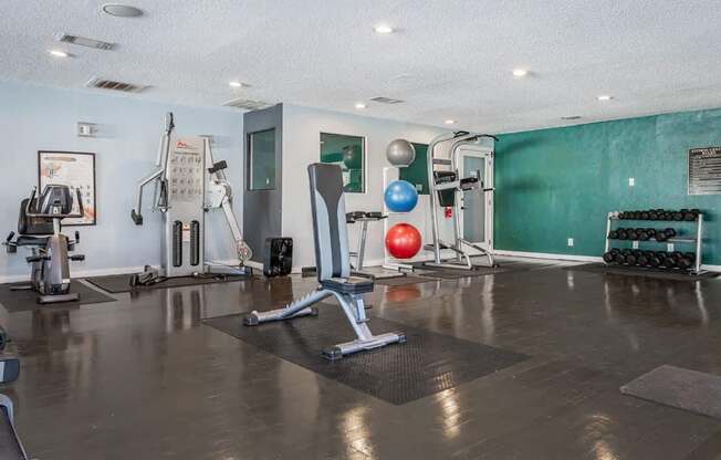 A gym with a variety of equipment including weights and exercise balls.
