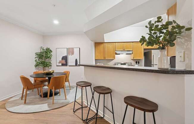 A kitchen with a bar area and a dining table with chairs.