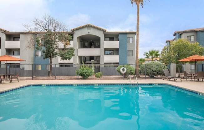 A swimming pool in front of a building with a palm tree.